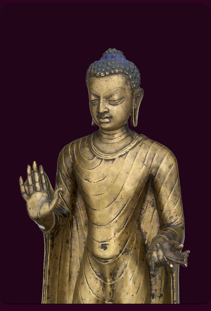 Golden sculpture of a buddha with blue coiled hair and long drooping earlobes